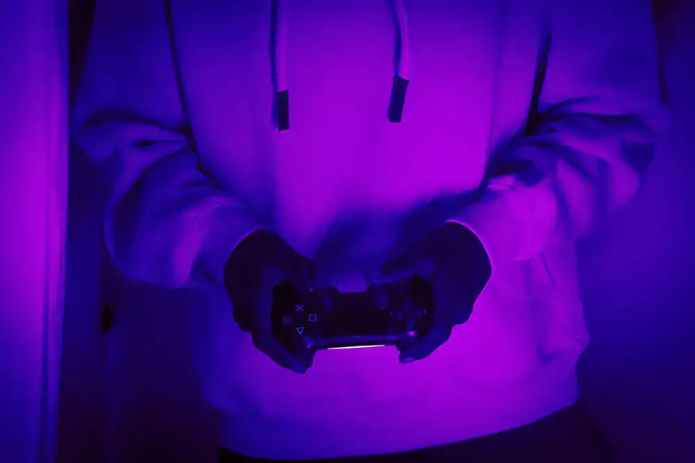 Close up of hands holding colorful controllers in a dark room