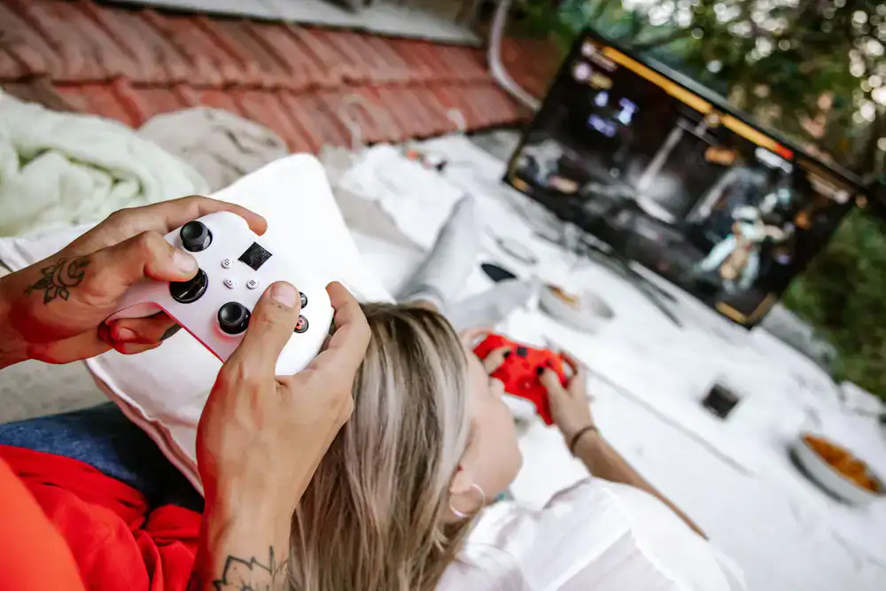 Two friends holding controllers and pointing excitedly at a television screen