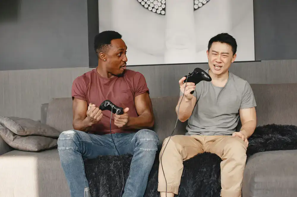 Four friends laughing and playing a frantic co-op game together on a couch